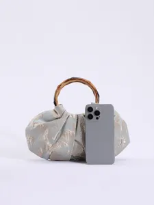 Gedetailleerd overzicht van de geplooide stoffen handtas met bamboe handvat, lichtgroene accessoire.