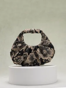 Elegante borsa jacquard nera con fiori dorati e perle su un piedistallo bianco