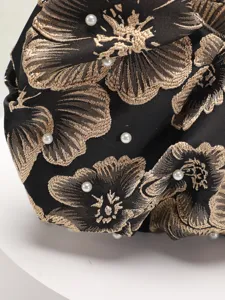 Dettaglio che mostra l'intricato ricamo floreale e gli accenti di perle sulla borsa