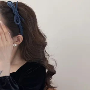 Detailed side view of a vintage blue flocked velvet bow headband on elegant wavy hair