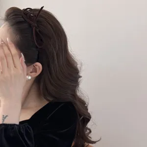 Close-up detail of a brown velvet bow headband showing retro wave design on hair