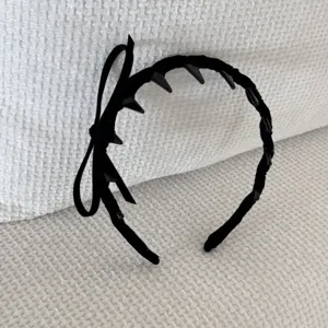 Detailed view of a black velvet headband with a bow and anti-slip inner spikes.