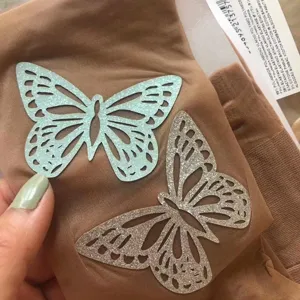 Close-up van huidskleurige panty met glittervlinderprints en samenstellingsetiket.