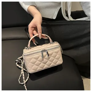 Dettaglio di borsa a scatola trapuntata a mano, con texture e tracolla a catena argento.