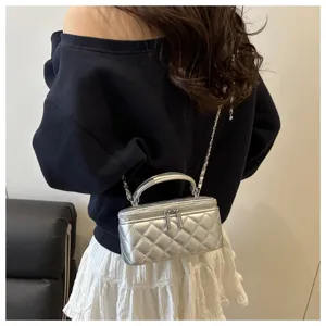Vista posteriore di una modella con borsa a scatola trapuntata argento con tracolla a catena