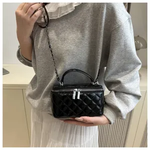 Primo piano di una borsa a scatola trapuntata nera con catena indossata da un modello.