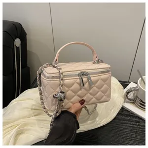 Primo piano di una borsa a scatola trapuntata a rombi rosa con tracolla a catena argento
