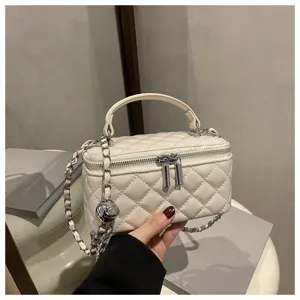 Primo piano di una borsa vanity trapuntata bianca con tracolla a catena e manico top.