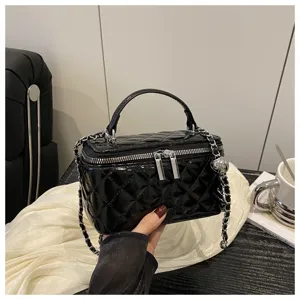 Primo piano di borsa a scatola trapuntata nera lucida con dettagli catena argento