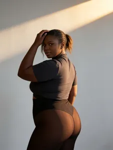 Professional detail view of black sheer thermal tights with peach butt lifting design on model