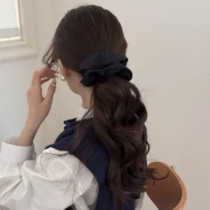 Elegante coletero de raso negro de gran tamaño peinado en coleta baja en una modelo asiática