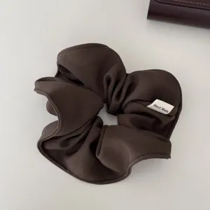 Elegante coletero de tela marrón oscuro con etiqueta hecha a mano y textura acanalada.