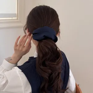 Elegante coletero azul marino de gran tamaño en una coleta de mujer con estilo minimalista