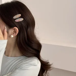 Gros plan de barrettes à cheveux ovales en acétate effet marbre sur cheveux bruns