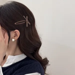 Detail view of a sweet brown bow hair clip worn on wavy brunette hair.