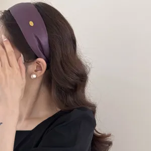 Close-up of vintage purple wide headband with gold label on Asian female model