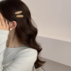 Détail de deux pinces à cheveux vintage en acétate ambré sur des cheveux brun ondulé