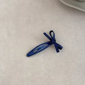 Close-up of a navy blue bow hair clip for girls, minimalist Korean style hair accessory.