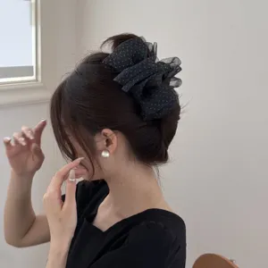 Side view of a large black polka dot organza hair scrunchie on a woman's bun hairstyle.