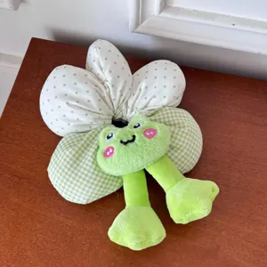 Detailed shot of a cute plush frog flower scrunchie with green polka dots and gingham patterns