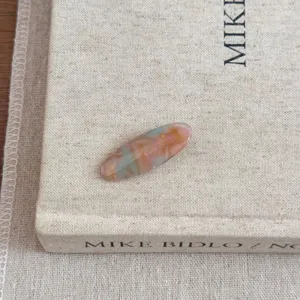 Vue macro d'une pince à cheveux ovale en acétate coloré sur un livre à grain texturé.