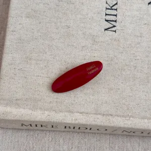 Vue détaillée d'une pince à cheveux ovale rouge en acétate sur une couverture de livre