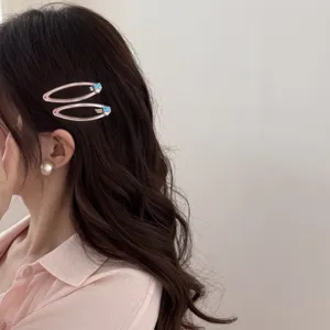 Gros plan de barrettes à cheveux roses avec zircon bleu et perle sur le modèle