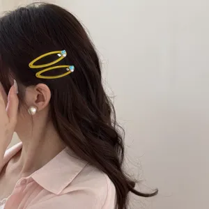 Gros plan de barrettes jaunes avec perle et zircon sur cheveux foncés ondulés