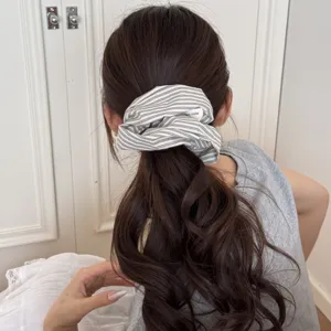 Back view of a wavy ponytail styled with a minimalist striped fabric scrunchie accessory