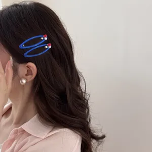 Vue latérale de pinces à cheveux bleues avec perles et pierres rouges sur cheveux