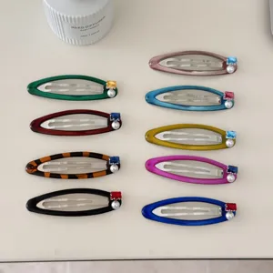 Barrettes ovales colorées avec perles et zircons sur un bureau blanc élégant