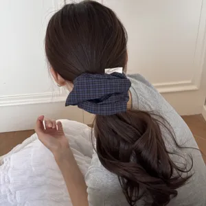 Back view of a stylish checkered blue and black fabric scrunchie on a ponytail tie