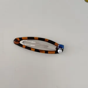 Gros plan d'une barrette à cheveux en écaille avec un zircon bleu et une perle blanche.