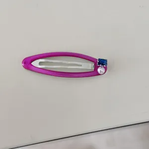 Gros plan détaillé d'une pince à cheveux rose avec perle et détail en zircon bleu