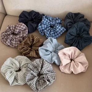 Collection of colorful checkered and striped scrunchies on a soft neutral fabric background