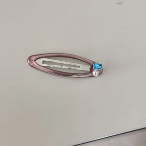 Vue détaillée de la pince à cheveux rose en résine avec zircon bleu et perle élégante