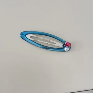 Vue détaillée d'une pince à cheveux bleue avec zircon rose et perle blanche élégante