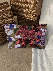 Close-up of floral sequined embroidery on the flap of an elegant evening envelope clutch bag.