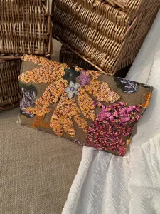Detailed view of floral sequin embroidery on an elegant envelope-style evening clutch bag.
