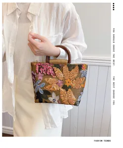 Vista dettagliata di una borsa etnica in lino a fiori con manici in legno indossata