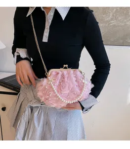 Gros plan d'un sac sous les bras à fleurs roses avec perles et chaîne dorée.