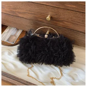 Detailed view of the black mesh ruffled evening clutch with a gold-tone handle and jewel clasp.