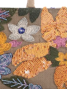 Close-up detail of exquisite sequin floral embroidery on a woven fabric tote bag.