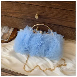 Close-up detail of a light blue ruffled tulle evening clutch with a gold metal handle.