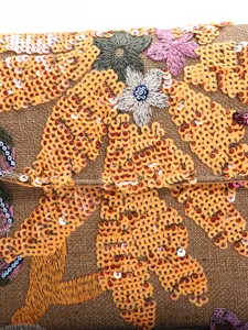 Close-up of intricate floral embroidery and shimmering orange sequins on an evening bag