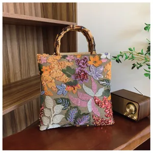 Detailed floral embroidery and sequins on linen handbag with authentic bamboo handle.