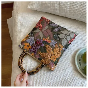 Detail of linen handbag with bamboo handle and colorful floral sequin embroidery
