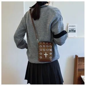 Detailed view of dark style crossbody square bag with silver eyelets and skull cross ornament