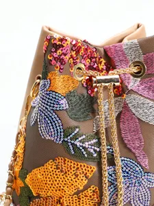 Detailed view of intricate floral embroidery and colorful sequins on a mesh bucket bag