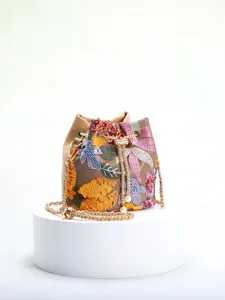 Detailed macro view of colorful floral embroidery and sequins on elegant tan bucket bag.